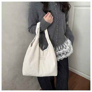 Détail du sac cabas plissé blanc avec rayures verticales et étiquette fashion