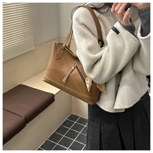 Detail of brown leather tote bag with white stitching, decorative silk scarf and tassel