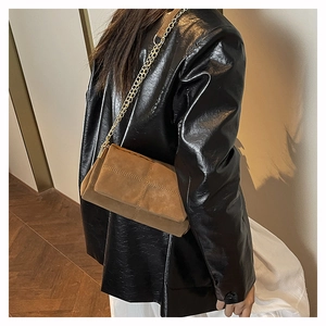 Detail of brown faux suede crossbody bag with cross-stitch pattern and gold chain strap