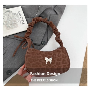 Detail of leopard print handbag featuring a silver butterfly buckle and ruffled shoulder strap