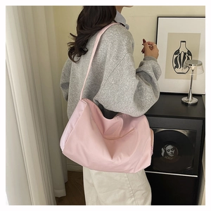 Detail of light pink large nylon tote bag featuring external zipper and wide shoulder strap