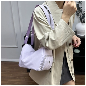 Close-up of a light purple waterproof nylon crossbody bag with a round front pocket and wide strap