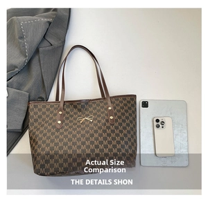 Brown tote bag detail with monogram M pattern and gold bow charm beside a tablet