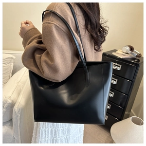 Photo lifestyle d'un grand sac cabas noir en similicuir avec longues anses en intérieur