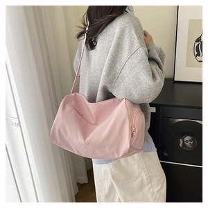Pink waterproof nylon gym bag with wide shoulder strap shown being worn by a model