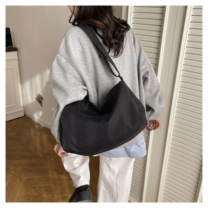 Model view showing the back side of a black waterproof nylon fitness gym bag with strap
