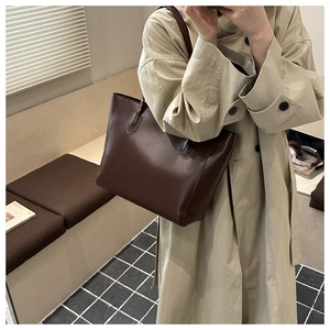 Détail d'un grand sac fourre-tout marron foncé porté par un mannequin en intérieur