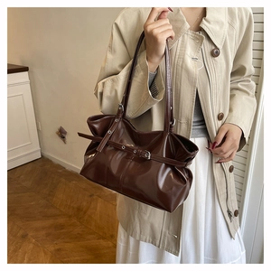 Detail of glossy brown faux leather tote bag showing rich texture and decorative strap