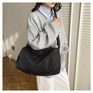 Detail of a black nylon crossbody bag with adjustable wide strap for daily city commute