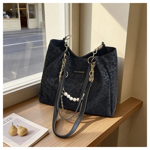 Detail of leopard print tote bag with pearl chain and gold metal link strap on wood