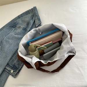 Grand sac cabas en velours côtelé marron contenant des livres et une tablette