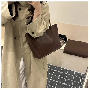 Détail d'un sac cabas marron vintage porté avec un trench-coat kaki pour le style quotidien