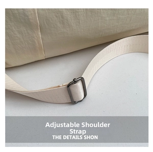 Detail of adjustable shoulder strap with matte metal buckle on beige nylon gym bag