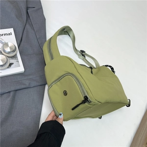 Green nylon crossbody bag with adjustable strap shown in a minimalist lifestyle setting