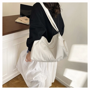 Side view of a large white vintage style Boston bag on a female model for daily commute