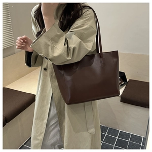 Sac fourre-tout marron foncé minimaliste porté avec un trench beige pour un style élégant