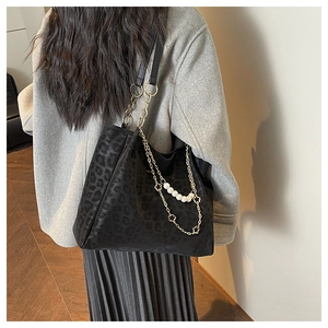 Detail of black leopard print tote bag with white pearls and gold chain strap decoration