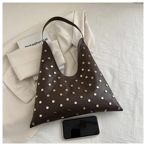 Detail of dark brown leather tote bag with gold rivets and hobo style shoulder strap