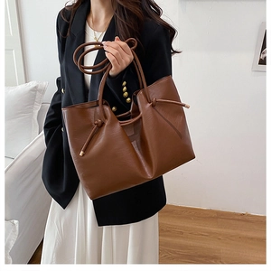 Detailed close-up of brown faux leather tote bag showing drawstrings and dual shoulder straps