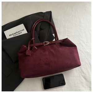 Detail of burgundy suede tote bag featuring metallic buckle and minimalist texture