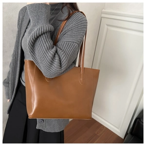 Photo portée d'un grand sac cabas minimaliste en cuir marron avec de longues anses