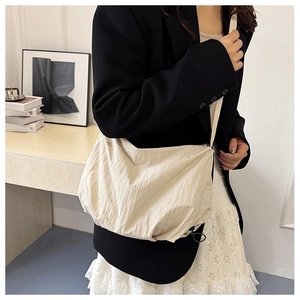 Close-up of a beige nylon tote bag featuring crinkled texture fabric and a slim strap
