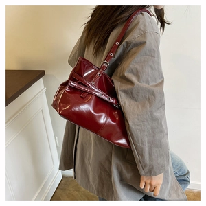 Dettaglio della borsa a spalla in pelle cerata bordeaux scuro con occhielli in metallo lucido