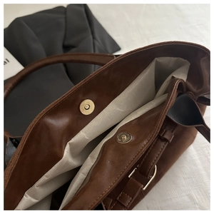 Detail of the magnetic snap closure and interior lining of the brown suede tote bag