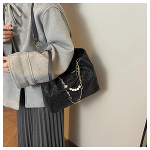 Close-up of black leopard print tote bag with gold chain and pearl strap detail
