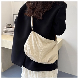 Side view of beige nylon tote bag with pleated texture and drawstring detail on model