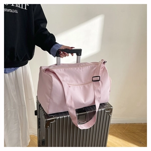 Pink travel bag detail showing the rear strap sleeve attached to a silver suitcase handle