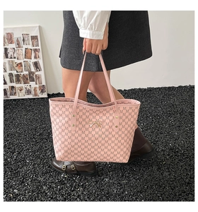 Detail of pink tote bag featuring M-letter print and golden bow metal accessory