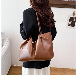 Brown pleated tote bag featuring knotted straps and metallic drawstring detail for daily commute