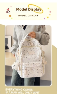 Detailed view of white canvas backpack with star patterns and plush bear keychain accessory