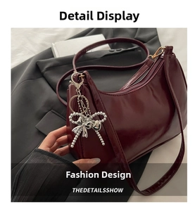 Detail of burgundy patent leather shoulder bag with silver bow charm and metal zipper