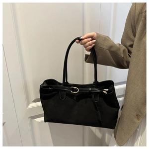 Detail of black suede tote bag with golden metal buckle and leather shoulder strap