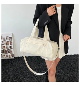 Detailed side view of off-white nylon gym bag with adjustable strap on a model