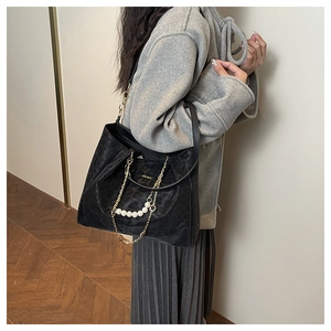 Detail of black tote bag featuring gold chain, pearl accents and subtle leopard texture