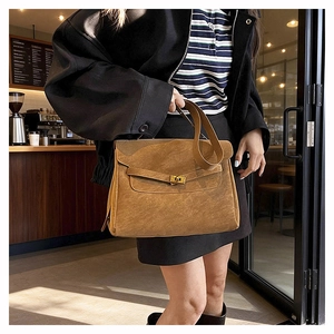 Close-up of brown vintage Kelly bag with gold twist lock and leather shoulder strap