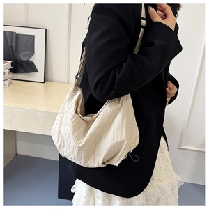Detail view of large cream nylon tote bag with pleated texture and wide strap