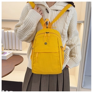 Macro detail of vibrant yellow nylon backpack with multi-functional zipper pockets