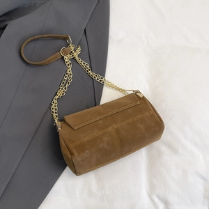 Brown suede shoulder bag with gold chain strap and parallel stitching on grey blazer