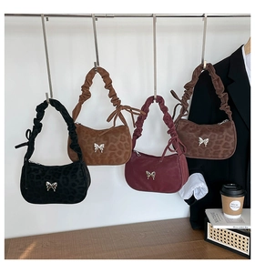 Detail of four leopard texture hobo bags with pleated handles and bow hardware in various colors