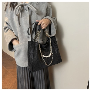 Detail of leopard print tote bag with gold chain and pearl charms on grey wool coat