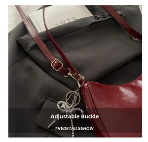 Detail view of red leather crossbody bag with silver pearl bow charm and buckle strap