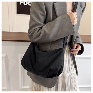 Detail view of a large black nylon tote bag showing soft texture and crossbody strap