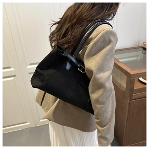 Woman wearing a large black suede tote bag with double shoulder straps in a retro style