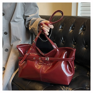 Dettaglio borsa tote in pelle verniciata rosso scuro con fibbia in metallo e occhielli
