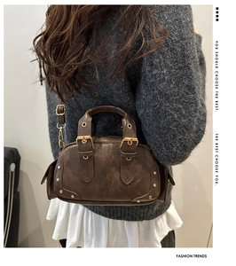 Close-up of vintage brown leather handbag with metal rivets and buckle details