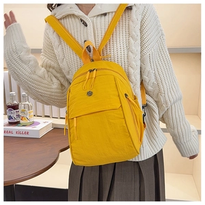 Detail of yellow nylon multi-functional backpack with metallic logo and side zipper pockets